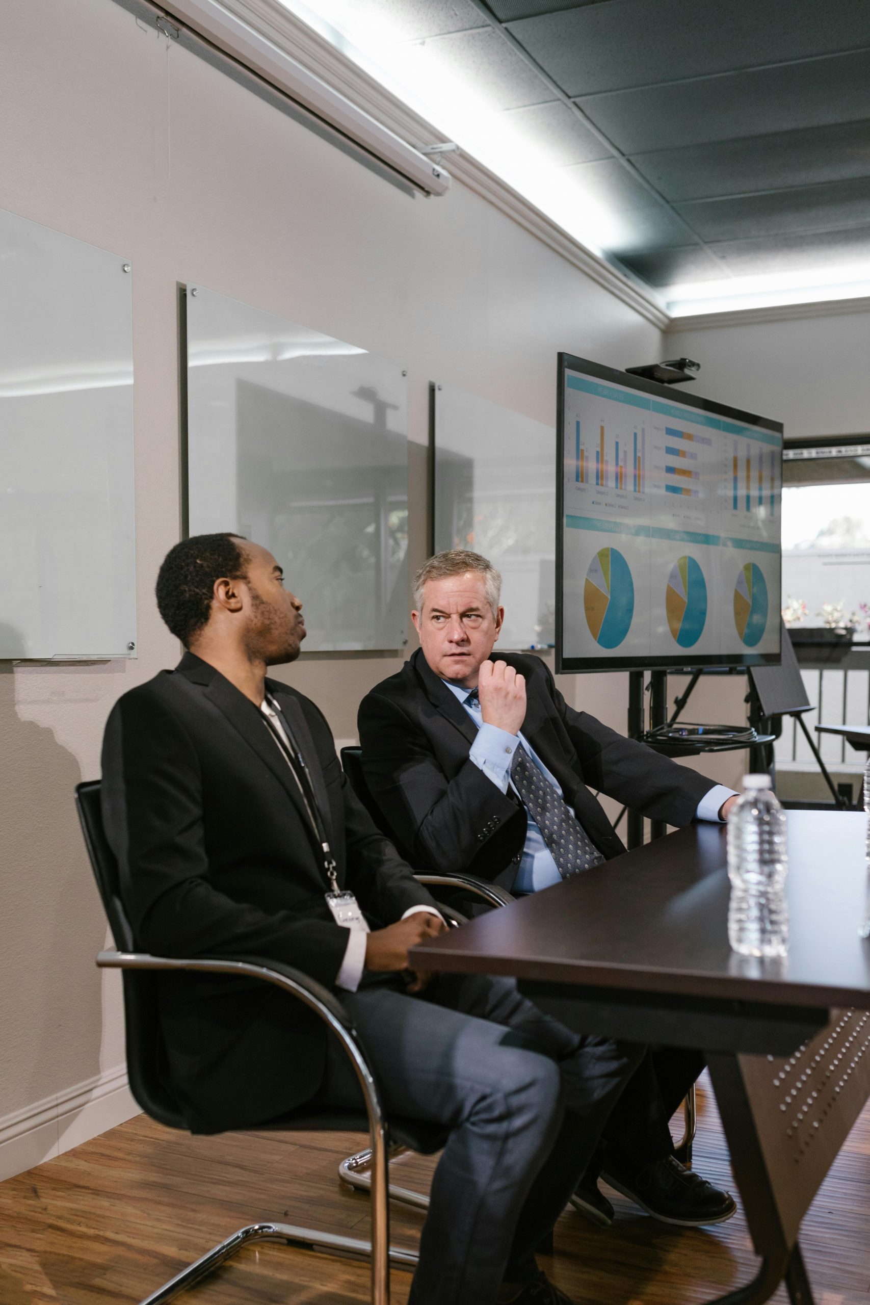 Two men in business attire engage in a professional discussion in a modern office.